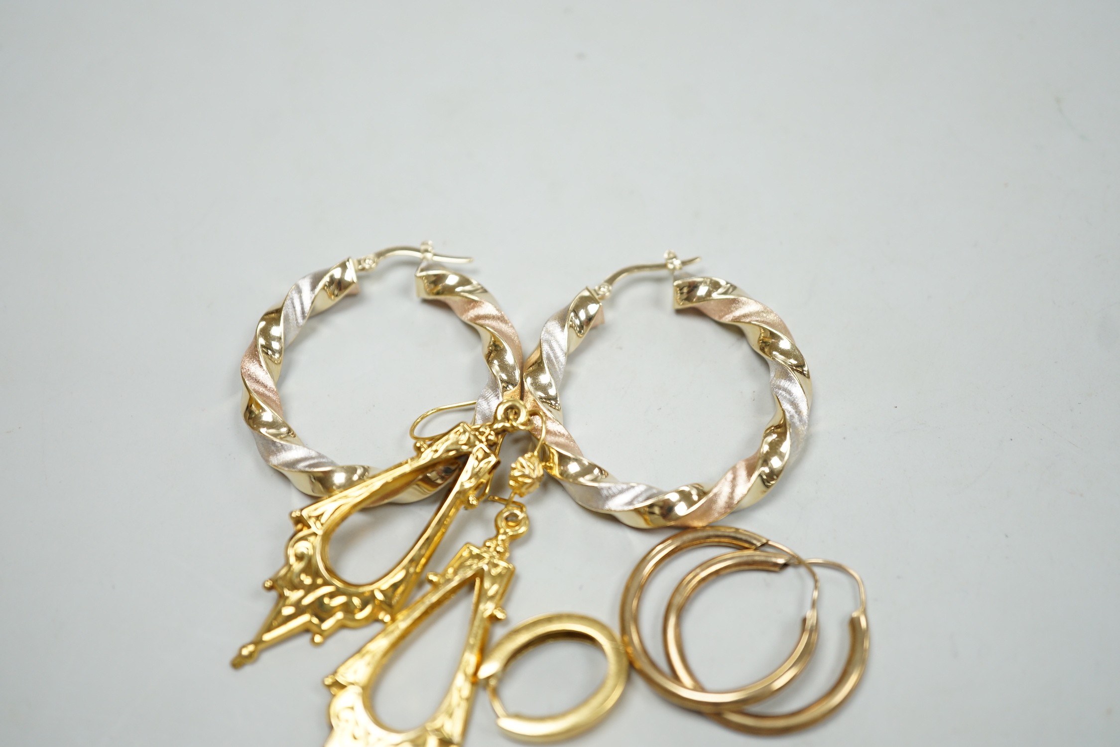 A modern pair of Italian three colour 14k hoop earrings, 35mm, 5.9 grams, a small pair of 750 oval earrings, 5.4 grams, a pair of 9ct gold Victorian style drop earrings, 2.7 grams and a pair of yellow metal hoop earrings